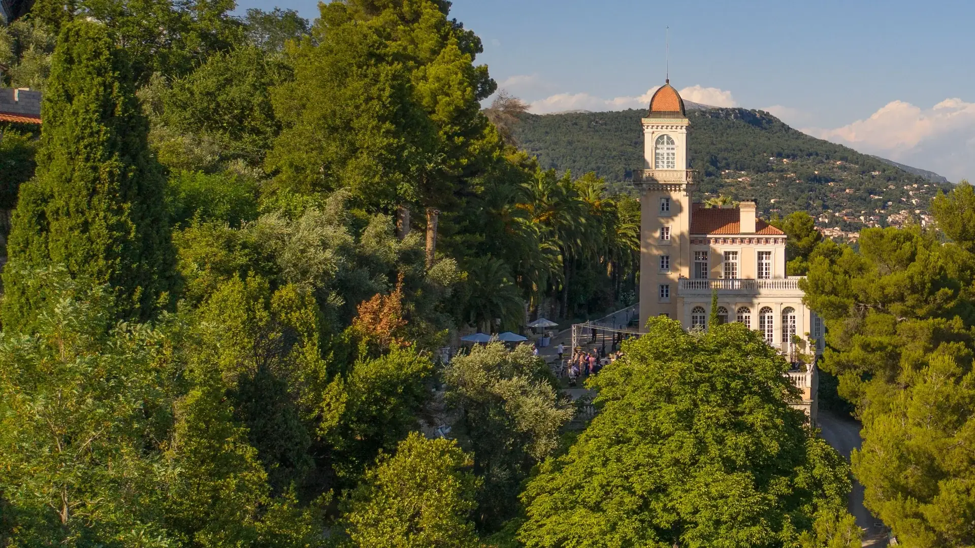 Château Saint-Georges, a perfumer’s nineteenth-century villa with a round tower and domed cupola, rising from pine and palm trees on a hillside above Grasse in evening light.